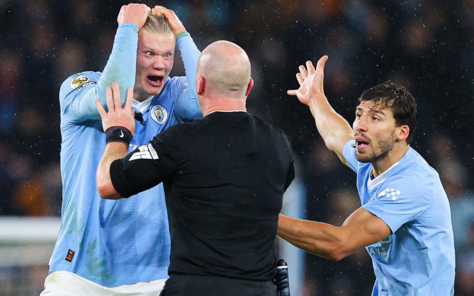 Referee Simon Hooper is surrounded by Erling Haaland, Mateo Kovacic and Ruben Dias