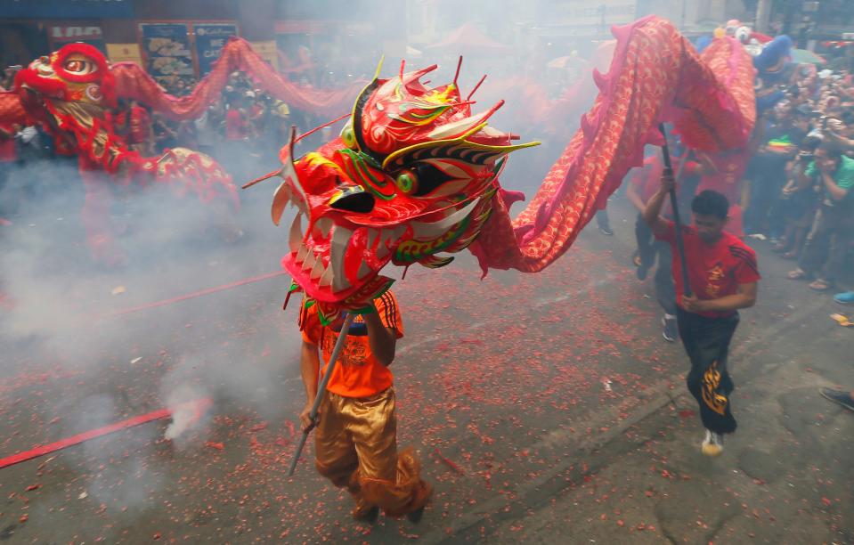 Dragon and lion dancers perform amidst exploding firecrackers in front of a business establishment in celebration of the Chinese Lunar New Year, Saturday, Jan. 28, 2017, in the Chinatown area of Manila, Philippines. This year is the Year of the Rooster on the Chinese lunar calendar. (AP Photo/Bullit Marquez)