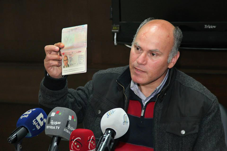 In this photo released by the Syrian official news agency SANA, Austrian lawyer identified as Anton Sander, shows his passport during a press conference, in Damascus, Syria, Friday April 11, 2014. Syria's state news agency SANA said Friday that authorities liberated an Austrian lawyer identified as Anton Sander, whom it said had been held by rebels in the central city of Homs for the past four months. SANA said Sander was in Homs visiting friends when he was taken by opposition fighters. It said he recently fled from his captors and was able to flee the neighborhood with the help of authorities. (AP Photo/SANA)