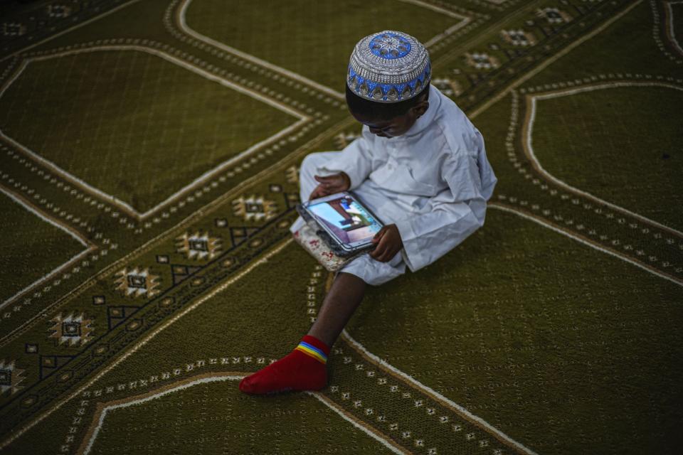 Un niño musulmán observa su tableta en la mezquita tras las oraciones, el viernes 16 de febrero de 2024, en La Habana, Cuba. La única mezquita en La Habana abrió sus puertas en 2015, y la comunidad musulmana ha crecido a unas 2.500 personas en todo el país. (AP Foto/Ramón Espinosa)