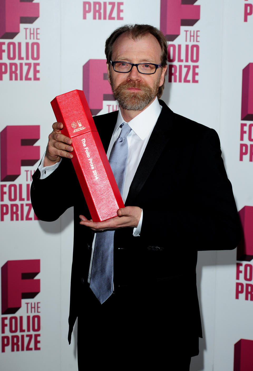 George Saunders holds up a trophy after winning the Folio Prize at the St Pancras Renaissance Hotel in London, Monday, March 10, 2014. The American writer has won the 40,000 pound ($67,000) Folio Prize for literature with his humorous and disturbing short-story collection "Tenth of December." The chair of the judging panel, poet Lavinia Greenlaw, said Monday that Saunders' "darkly playful" stories explore "the human self under ordinary and extraordinary pressure." Saunders beat seven other finalists, including Kent Haruf, Rachel Kushner, Anne Carson and Eimear McBride. (AP Photo/PA, Ian West) UNITED KINGDOM OUT