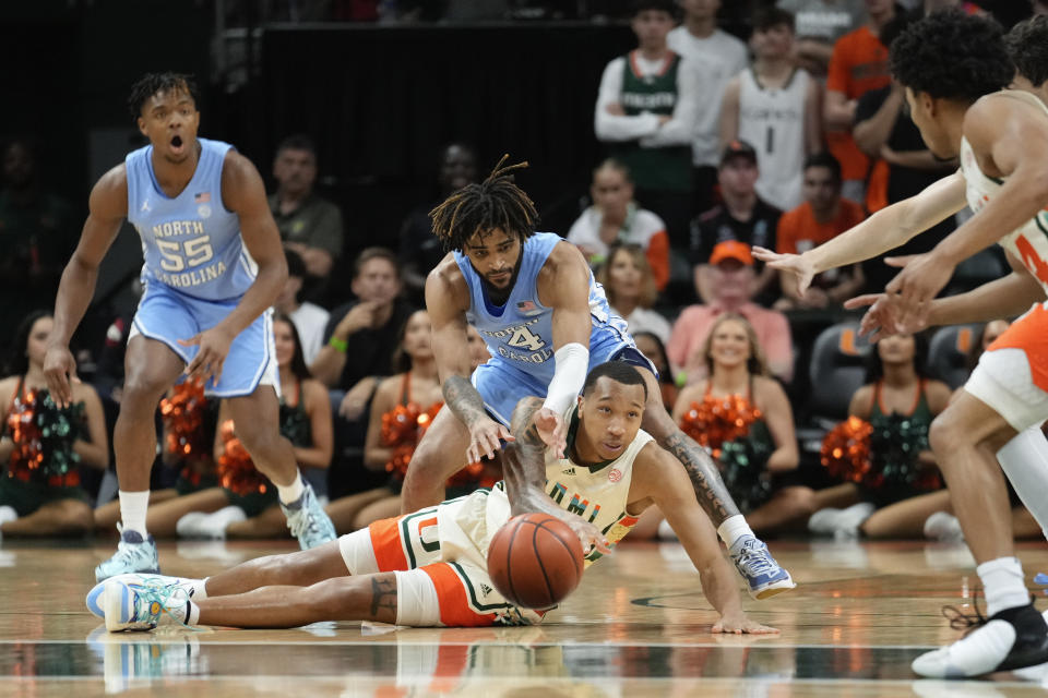 Miami guard Matthew Cleveland (0) makes a pass from the ground under pressure from North Carolina guard RJ Davis (4) during the first half of an NCAA college basketball game, Saturday, Feb. 10, 2024, in Coral Gables, Fla. (AP Photo/Rebecca Blackwell)