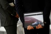 Employee stands in front of a Porsche 911 sports car on display at its dealership during a news conference in Seoul