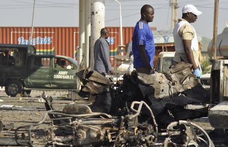 A military vehicle and people pass site of an explosion at a police station in Kano November 15, 2014. REUTERS/Stringer