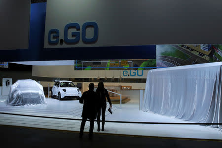 People talk at the e.GO booth ahead of the 89th Geneva International Motor Show in Geneva, Switzerland March 4, 2019. REUTERS/Denis Balibouse