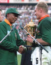 FILE - In this June 24, 1995 file photo, South African rugby captain Francios Pienaar, right, receives the Rugby World Cup from President Nelson Mandela after they defeated New Zealand 15-12 in the final at Ellis Park, Johannesberg, South Africa. Siya Kolisi was a 4-year-old child when South Africa won its first Rugby World Cup title in 1995 but he remembers the national euphoria of the Springboks' second World Cup title in 2007. The first black player appointed as Springboks captain gets his chance at history when he leads South Africa against England in the final on Saturday, Nov. 2, 2019 in Yokohama Japan. (AP Photo/Ross Setford,File)
