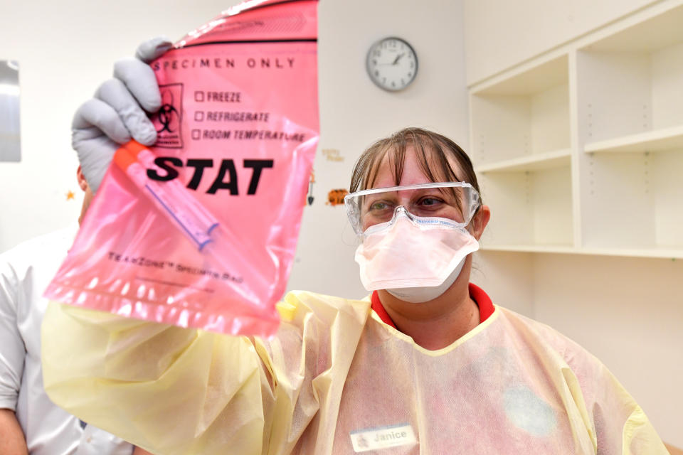 Picture of a woman holding up COVID-19 swab tests