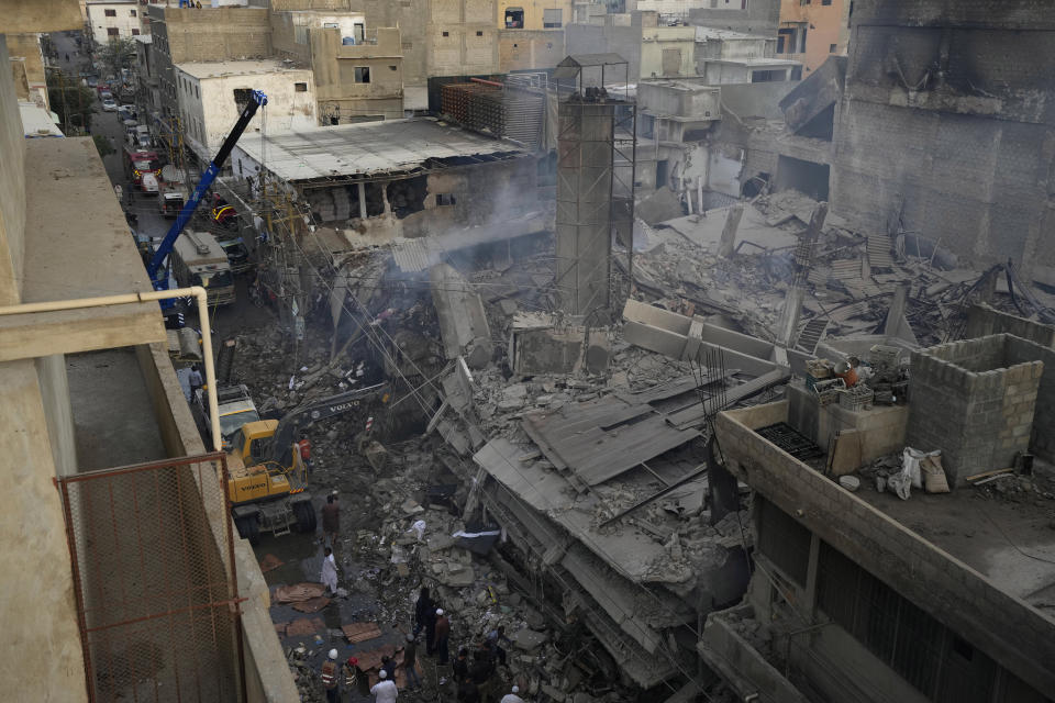 Rescue workers use heavy machinery to clear the rubble at the site of a fire, in Karachi, Pakistan, Thursday, April 13, 2023. A massive fire broke out in a garment factory in the southern Pakistan port city of Karachi. The cause of the blaze, which ripped through the factory Wednesday night and eventually caused it to collapse, was not immediately known, rescue officials and police said. (AP Photo/Fareed Khan)