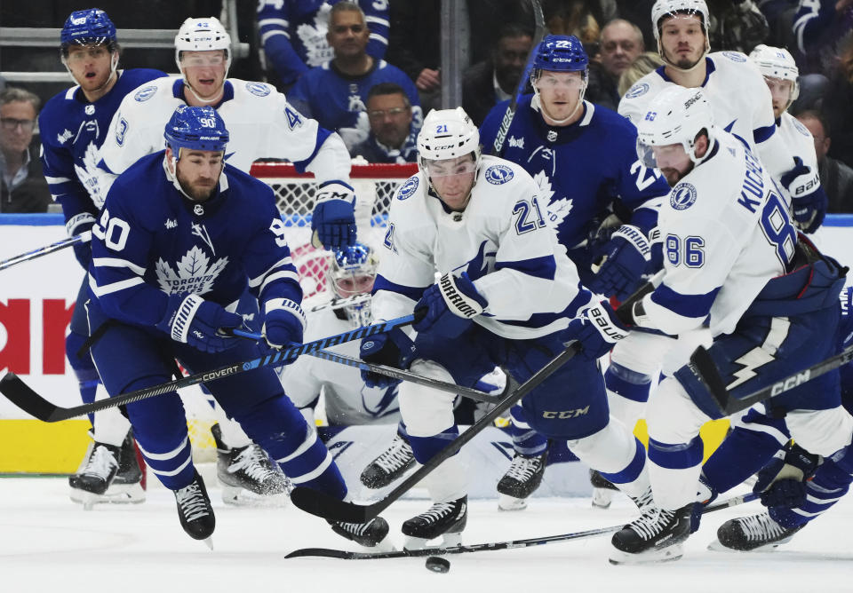 Tampa Bay Lightning right wing Nikita Kucherov (86) reaches for the puck as Toronto Maple Leafs forward Ryan O'Reilly (90) and Lightning forward Brayden Point (21) watch during the first period of Game 1 of a first-round NHL hockey playoff series Tuesday, April 18, 2023, in Toronto. (Nathan Denette/The Canadian Press via AP)