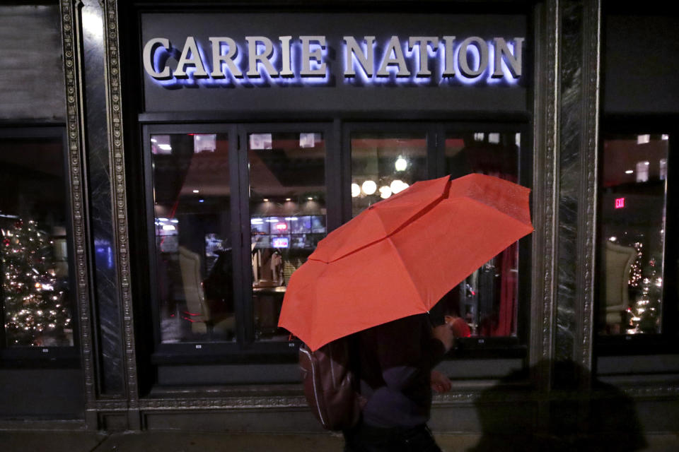 In this Dec. 10, 2019, file photo a woman holding an umbrella passes the Carrie Nation lounge in Boston, titled after the namesake of the woman supporting the temperance movement prior to the 1920 Prohibition ban on alcohol. (AP Photo/Charles Krupa, File)