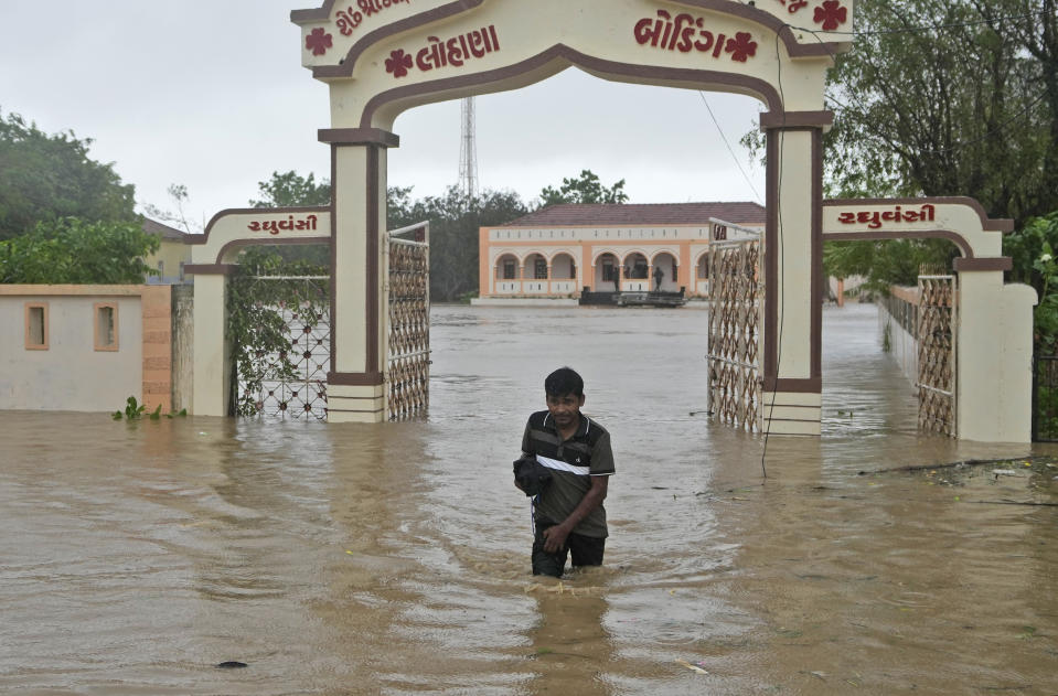 A man wades through flooded street following heavy winds and incessant rains after landfall of cyclone Biparjoy at Mandvi in Kutch district of Western Indian state of Gujarat, Friday, June 16, 2023. Cyclone Biparjoy knocked out power and threw shipping containers into the sea in western India on Friday before aiming its lashing winds and rain at part of Pakistan that suffered devastating floods last year. (AP Photo/Ajit Solanki)