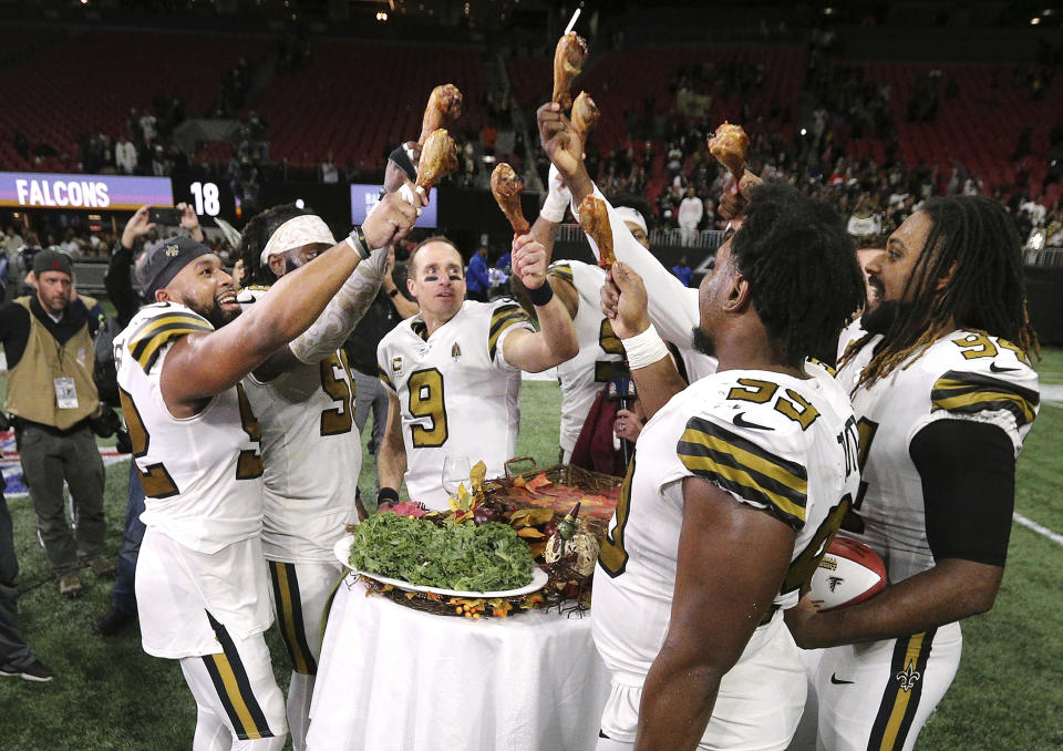 New Orleans Saints quarterback Drew Brees and teammates celebrate a 26-18 victory over the Atlanta Falcons with turkey legs on Thanksgiving Day, after an NFL football game Thursday, Nov. 28, 2019, in Atlanta. The Falcons clinched the NFC South title. (Curtis Compton/Atlanta Journal-Constitution via AP)