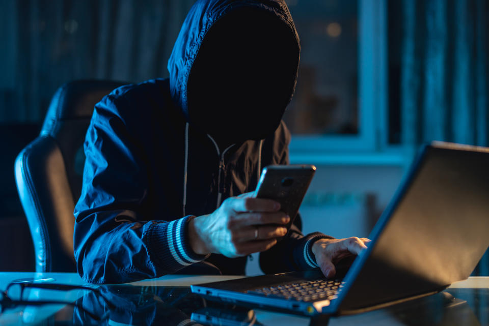 Anonymous hacker programmer uses a laptop to hack the system in the dark. Creation and infection of malicious virus. The concept of cybercrime and hacking database