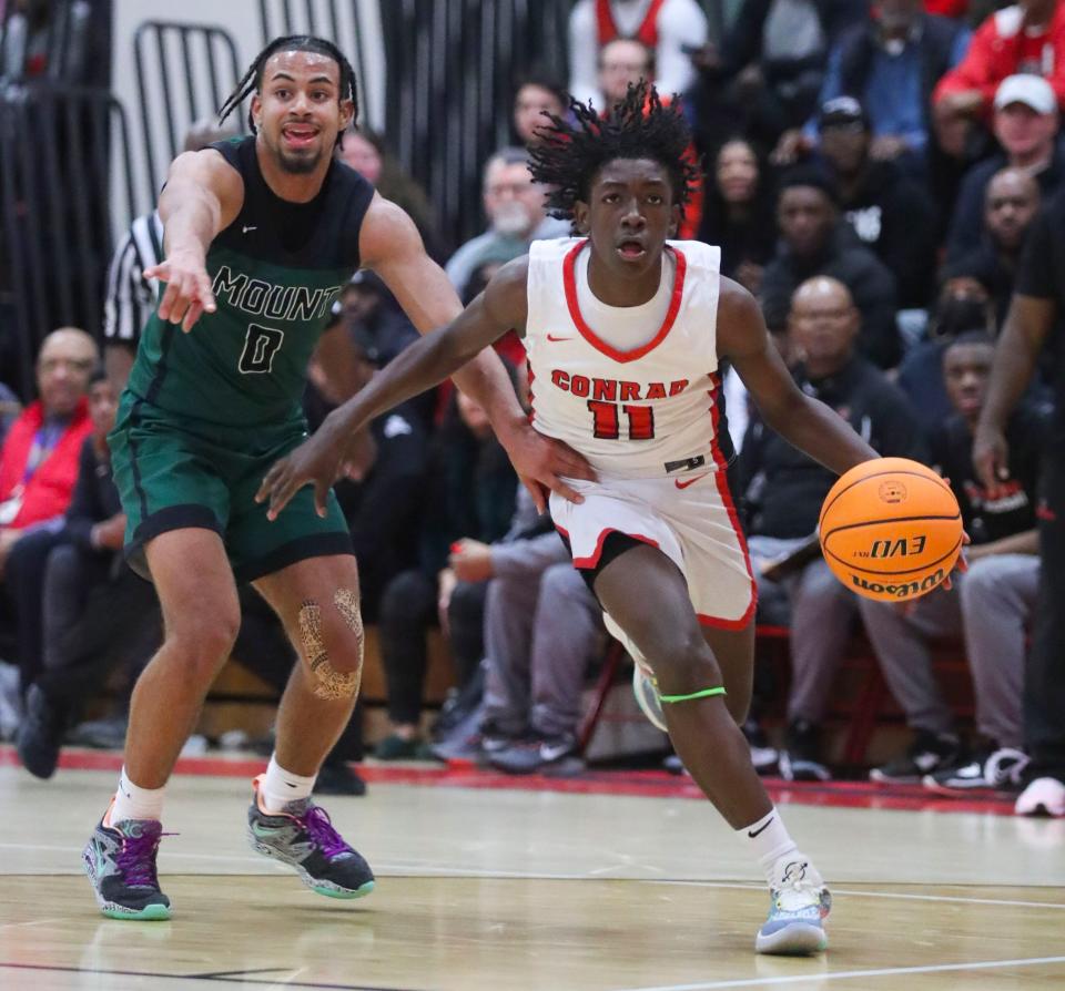 Mount Pleasant's Ronnie Potts (left) defends as Conrad's Latrell Wright moves toward the basket in the Green Knights' 69-58 win at Conrad in the opening round of the DIAA boys state tournament, Tuesday, Feb. 28, 2023.