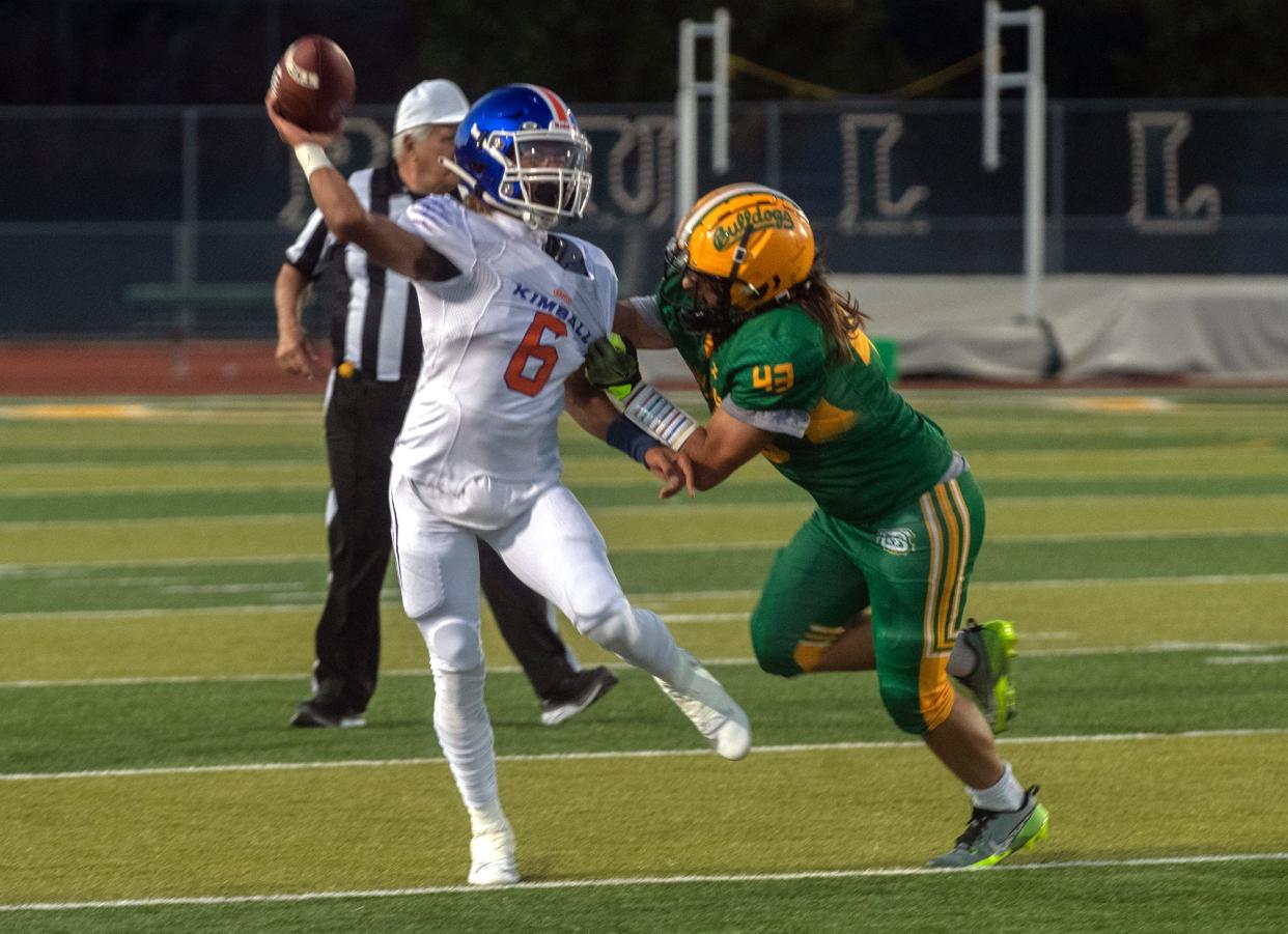 Kimball's Josiah Wilson, left, gets off a pass under pressure from Tracy's Maxwell Laird during a varsity football game at Tracy's Wayne Schneider Stadium in Tracy.