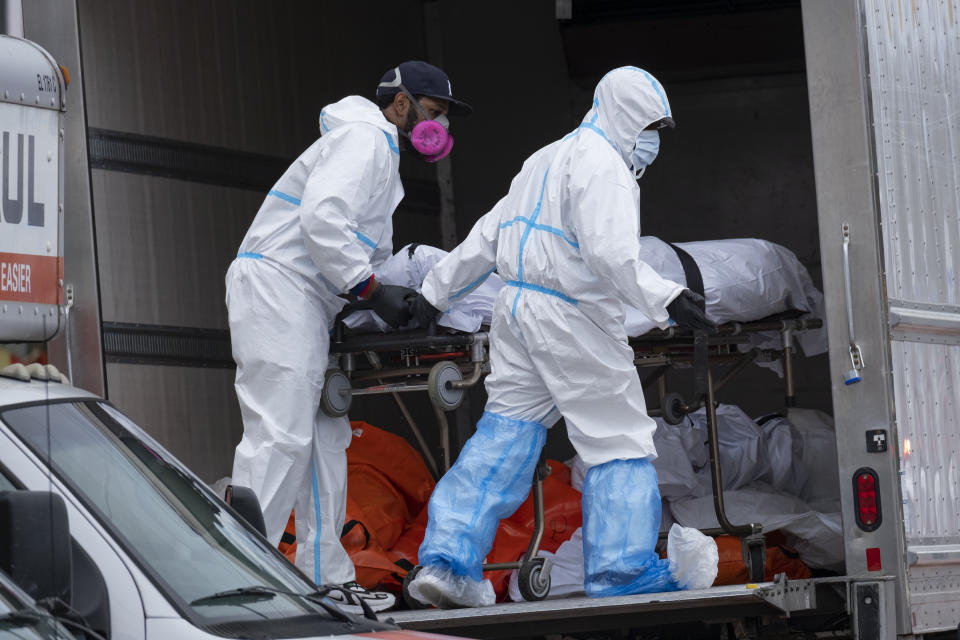 Men in suits are seen loading dead bodies into a truck. Source: AP