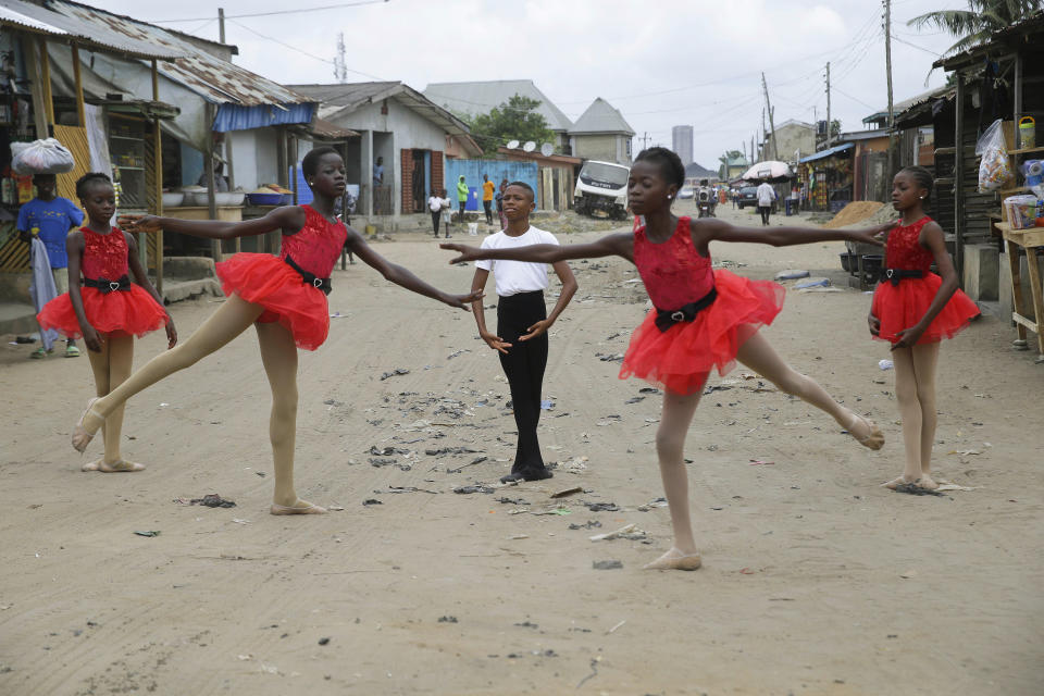 Ballet student Anthony Mmesoma Madu, center, stands in position as fellow dancers perform in the street in Lagos, Nigeria on Aug. 18, 2020. Cellphone video showing the 11-year-old Madu dancing barefoot in the rain went viral on social media. Madu’s practice dance session was so impressive that it earned him a ballet scholarship with the American Ballet Theater in the U.S. (AP Photo/Sunday Alamba)