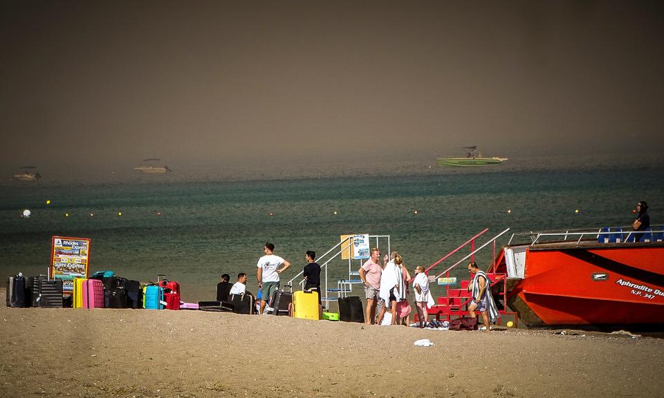 Tourists stand on a beach after being evacuated (AP)