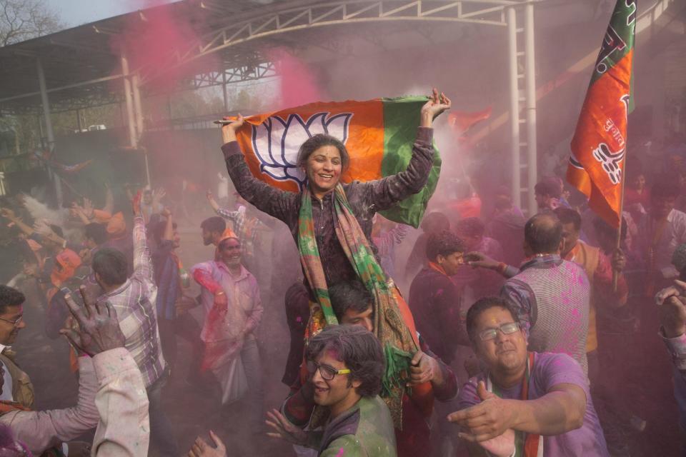 Bharatiya Janata Party supporters dance and throw colored powder as they celebrate at the party headquarters in New Delhi, India, Saturday, March 11, 2017. India's governing Hindu nationalist party was heading for major victories Saturday in key state legislature elections that are seen as a referendum on the performance of Prime Minister Narendra Modi's nearly 3-year-old government. (AP Photo/Tsering Topgyal)
