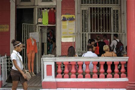 A schoolgirl past a private clothing outlet set up at the entrance of a home in Havana November 19, 2013. REUTERS/Desmond Boylan