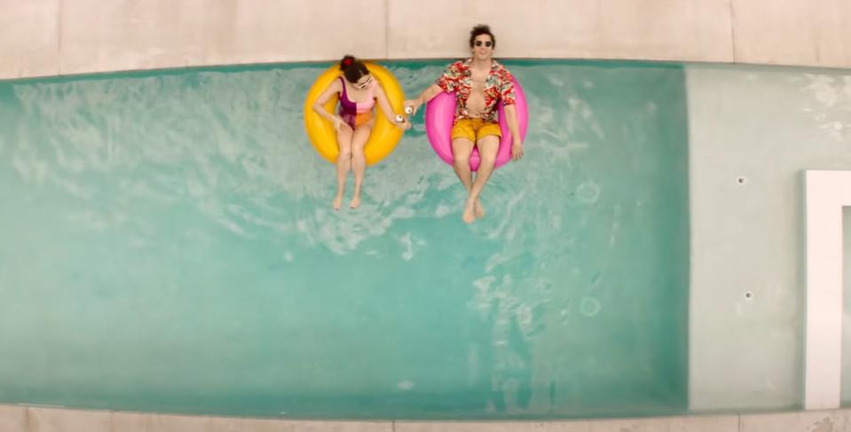 Cristin Milioti and Andy Samberg floating in innertubes in a pool from above in palm springs.