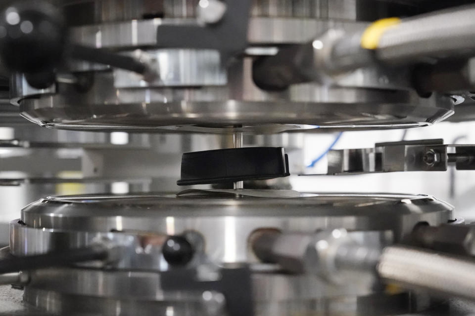 Una "galleta" con forma de disco de hockey, hecha de bolitas de vinilo calentadas, se coloca en una prensa para formar un disco de vinilo en las instalaciones de United Record Pressing, el jueves 23 de junio de 2022 en Nashville, Tennessee. (Foto AP/Mark Humphrey)