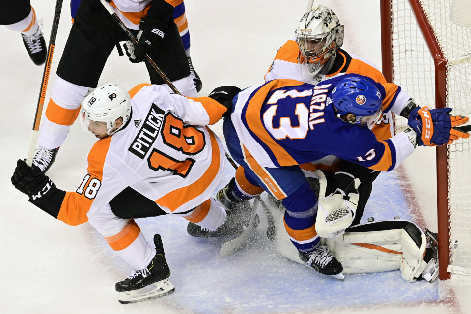 Philadelphia Flyers right wing Tyler Pitlick (18) battles New York Islanders center Mathew Barzal (13) in front of Flyers goaltender Carter Hart (79) during second-period NHL Stanley Cup Eastern Conference playoff hockey game action in Toronto, Saturday, Aug. 29, 2020. (Frank Gunn/The Canadian Press via AP)