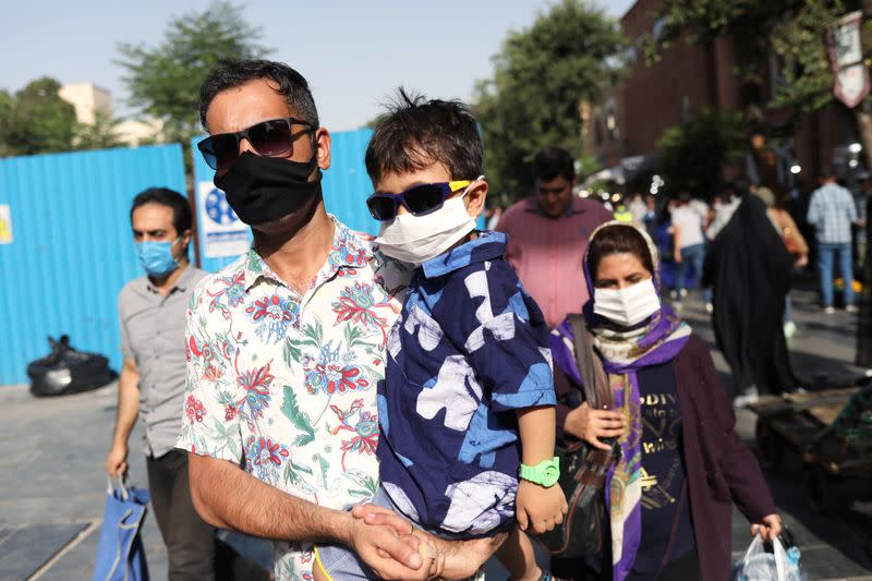 An Iranian man and his son wearing a protective face mask walks in a street, following the outbreak of the coronavirus disease (COVID-19), in Tehran