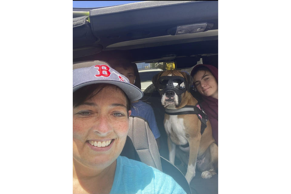 This 2021 photo provided by Cheri Burness shows Burness and her family, including dog Lilikoi, in a car in Honolulu. Hundreds of military families living near Pearl Harbor have complained of stomach pain, nausea and other health ailments amid concerns the Navy's water system may have been contaminated by a fuel leak.(Cheri Burness via AP)