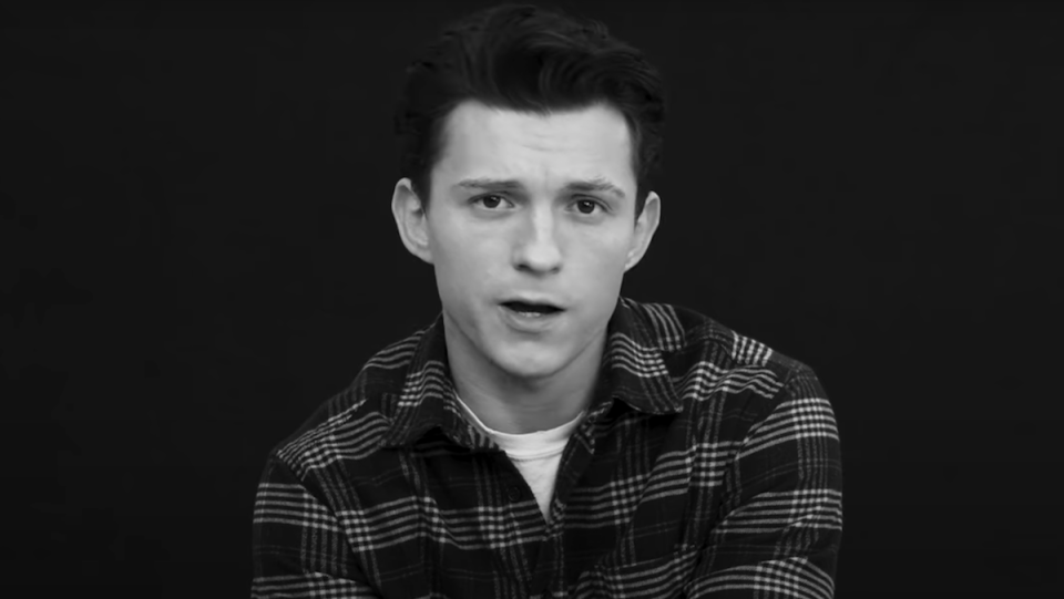 A black and white photo of Tom Holland speaking to camera