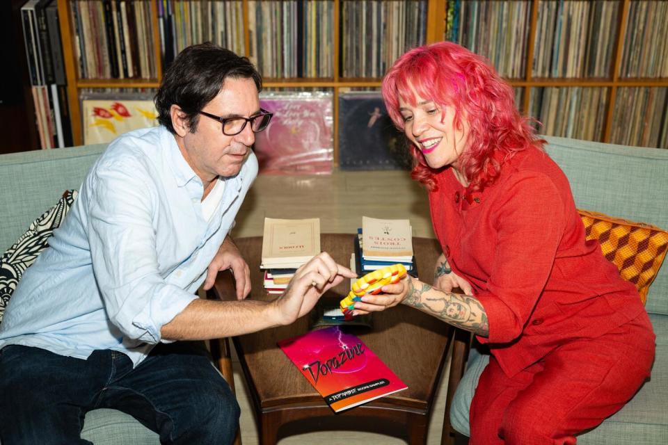 A man and woman talk about books and publishing in a home office.