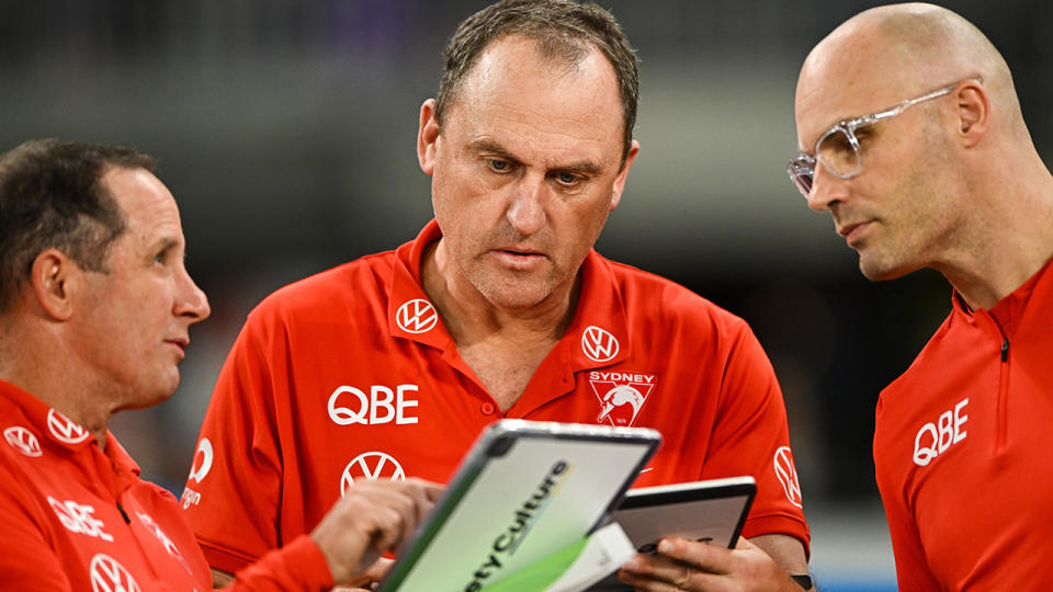 Swans coach John Longmire confers with his assistants.