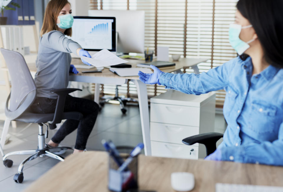 Two people in office passing documents with keeping a distance