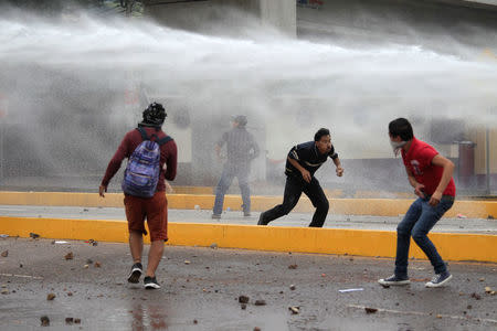 Supporters of Salvador Nasralla, presidential candidate for the Opposition Alliance Against the Dictatorship, avoid water fired from a police water cannon during a protest while waiting for official presidential election results in Tegucigalpa, Honduras November 30, 2017. REUTERS/Jorge Cabrera