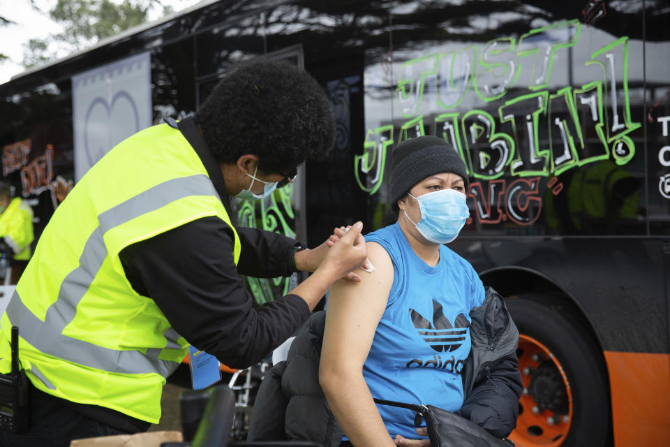A health worker administers vaccinations at a mobile clinic Oct. 7, 2021, in Auckland, New Zealand. New Zealand's doctors and teachers are among those who must soon be fully vaccinated against the coronavirus to continue working in their professions, the government announced Monday, Oct. 11, 2021. (Sylvie Whinray/New Zealand Herald via AP)