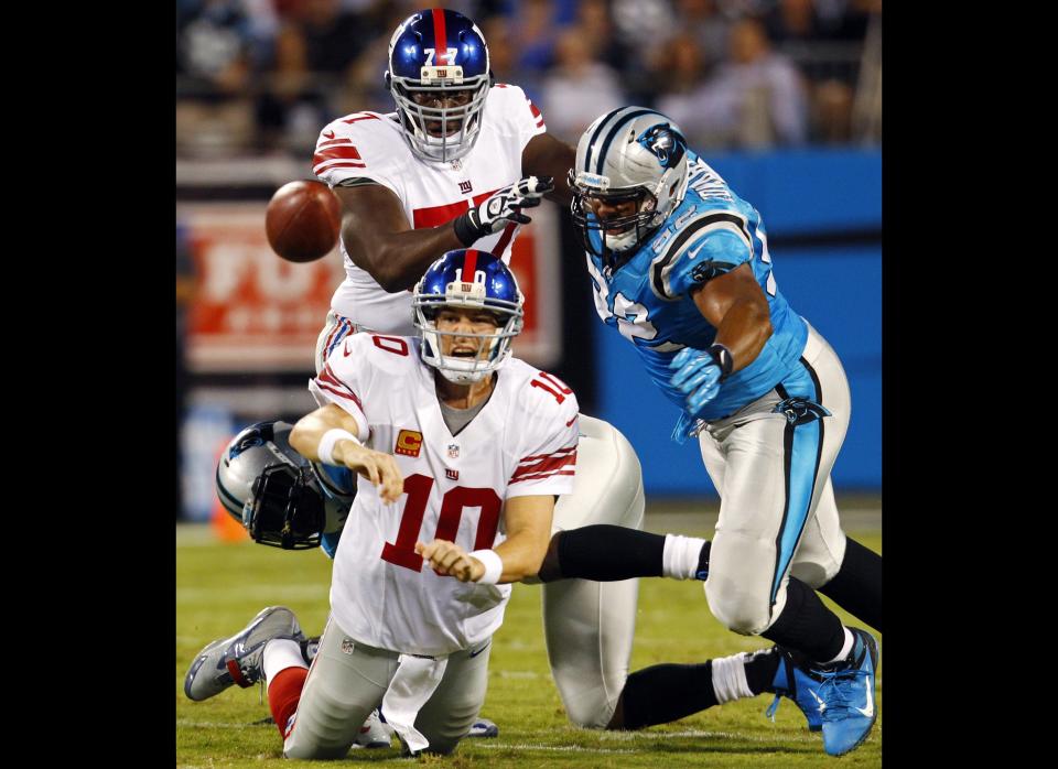 New York Giants quarterback Eli Manning (10) throws a pass under pressure from Carolina Panthers defensive tackle Dwan Edwards (92) during the first quarter of an NFL football game in Charlotte, N.C., Thursday, Sept. 20, 2012. 