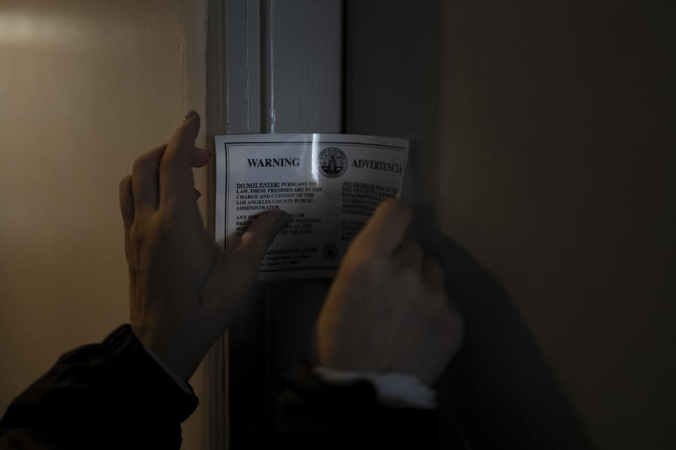 Arusyak Martirosyan, an investigator with the Los Angeles County Public Administrator's office, posts a seal on the door of a one-bedroom apartment in Los Angeles, Thursday, Nov. 16, 2023, after searching for clues that might lead to finding family members or relatives of a tenant who died in the hospital with no apparent next of kin. (AP Photo/Jae C. Hong)