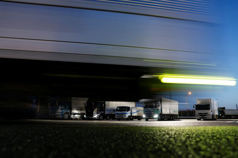 Delivery trucks are parked at a parking area along the highway in Chiba