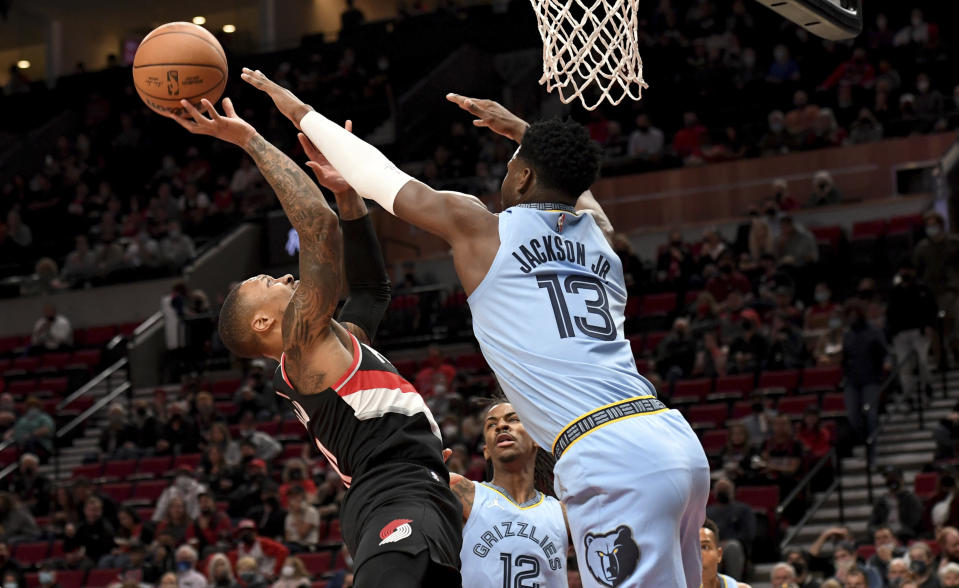 Portland Trail Blazers guard Damian Lillard, left, drives to the basket on Memphis Grizzlies forward Jaren Jackson Jr., right, during the first half of an NBA basketball game in Portland, Ore., Wednesday, Oct. 27, 2021. (AP Photo/Steve Dykes)