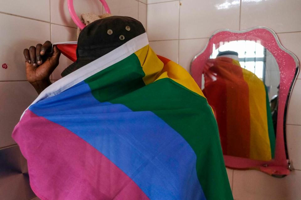 A gay Ugandan man covers himself with a pride flag as he poses for a photograph in Uganda Saturday, March 25, 2023. A prominent leader of Uganda's LGBTQ community on Thursday described anguished calls by others like him who are concerned for their safety after the passing of a harsh new anti-gay bill. (AP Photo)