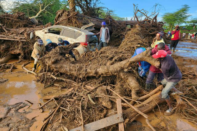 <p>AP Photo</p> People clean up after a dam burst in Kenya