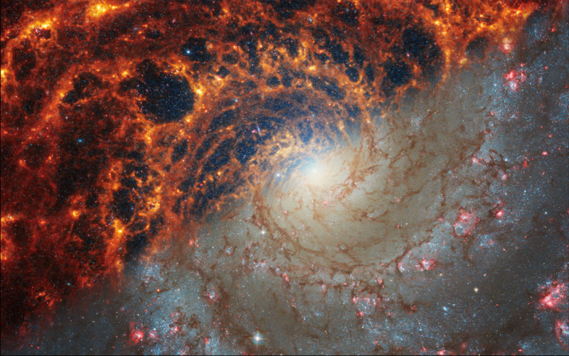 <cite>太空望遠鏡捕捉的螺旋星系「NGC628」影像，左上部分是韋伯的紅外光視野，右下部分是哈伯的可見光視野。（截自NASA官網）</cite>