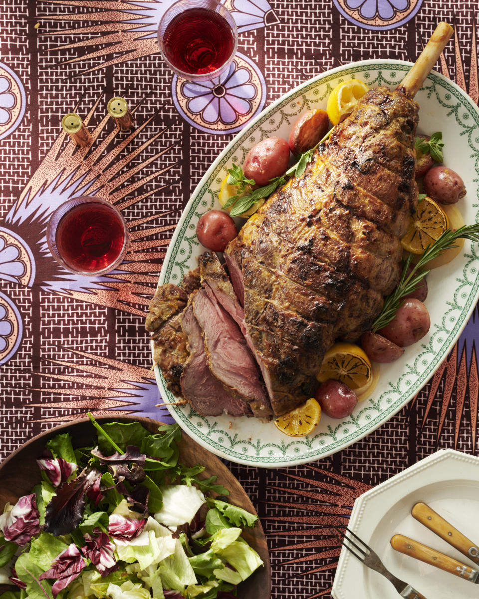 A plate of roasted lamb and a bowl of salad on a table.
