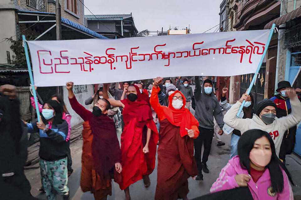 Youth activists and Buddhist monks participate in an anti-military government protest rally while holding a banner that reads in Burmese, "Who dares to stay on the opposite side of the people's will," on Tuesday, Feb. 1, 2022, in Mandalay, Myanmar. The new U.N. special envoy for Myanmar says violence has intensified since the military took power a year ago and sparked a resistance movement in the country. (AP Photo)