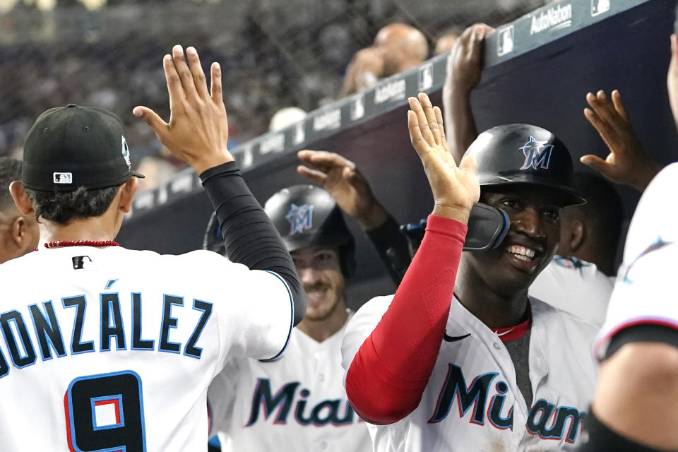 Miami Marlins' Jesus Sanchez, right, and Brian Anderson, center, are congratulated after scoring on a home run by Anderson during the fourth inning of the team's baseball game against the Milwaukee Brewers, Saturday, May 14, 2022, in Miami. (AP Photo/Lynne Sladky)