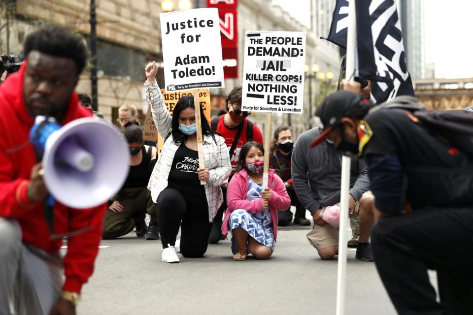 Abigail Garcia, 7, right, takes a knee with her mother, Judith Garcia, during a protest for Adam Toledo in downtown Chicago.