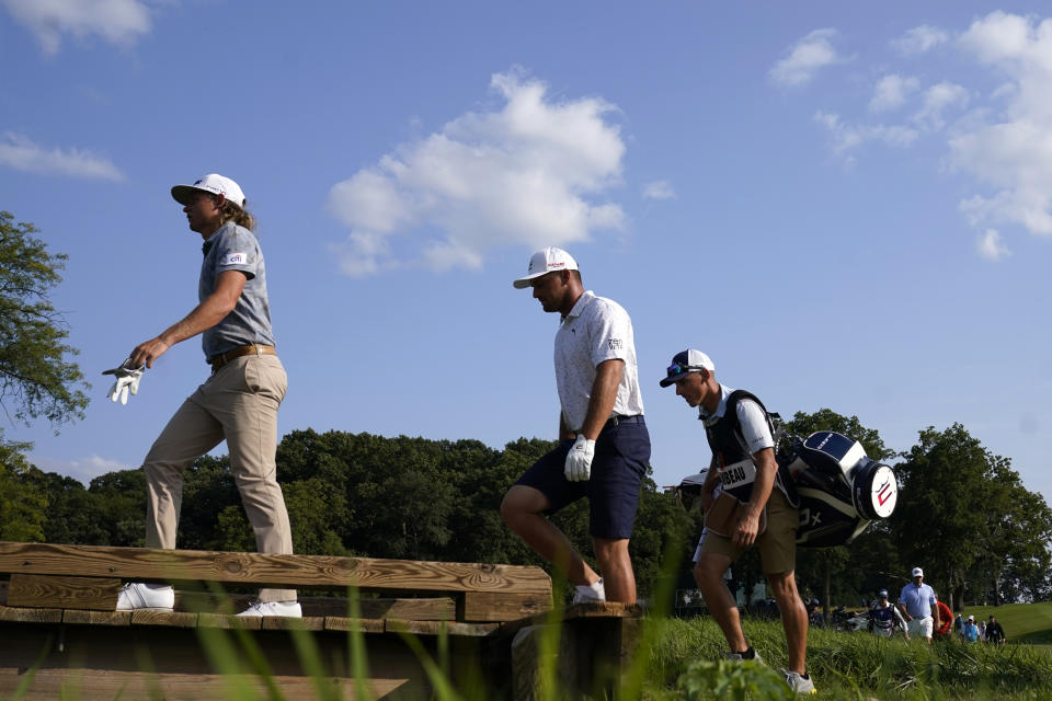 Cameron Smith, left, and Bryson DeChambeau, center, head to the 18th green during the first round of the LIV Golf Invitational-Chicago tournament Friday, Sept. 16, 2022, in Sugar Grove, Ill. (AP Photo/Charles Rex Arbogast)