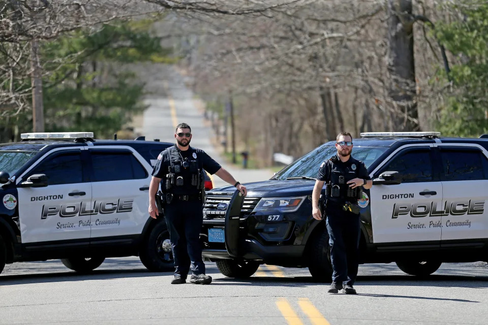 Two local police officers and patrol cars block the road as the FBI conducts a search of Teixeira's home in Dighton, Mass.