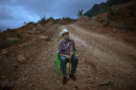 Alejandro Mejia, 80, rests in a chair alongside a dirt road after a visit to the site where the home he built once stood, in the hillside community of La Reina, Honduras, Saturday, June 26, 2021. The home that Mejia and his wife had lived in for 48 years was buried in an epic mudslide triggered by heavy rains brought on by Hurricanes Eta and Iota in November 2020. (AP Photo/Rodrigo Abd)