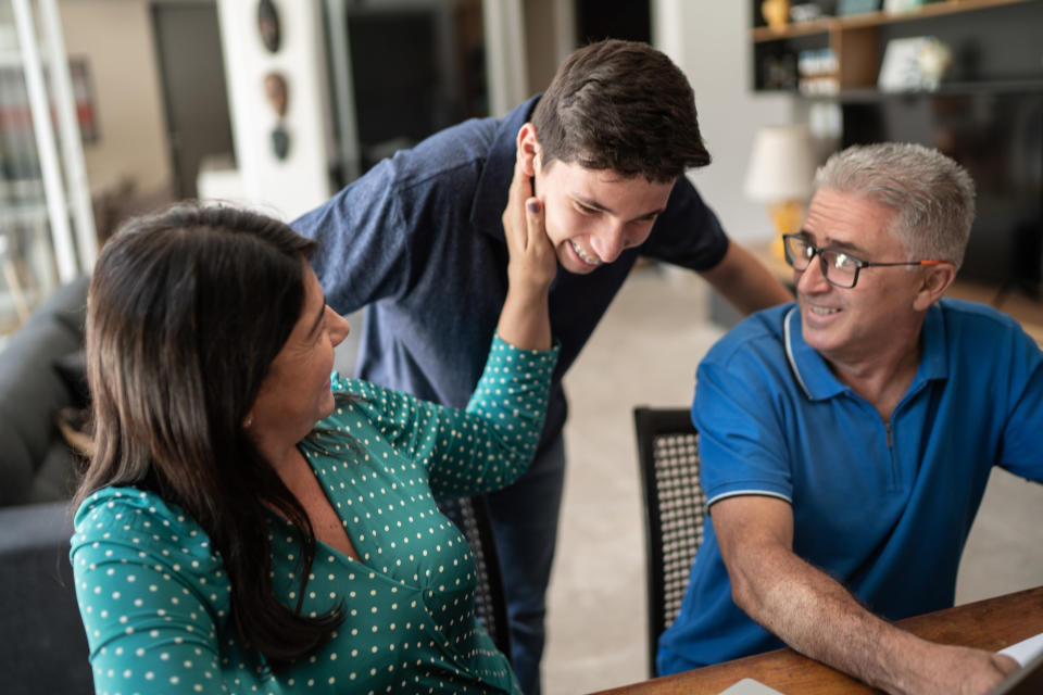 A mom and dad laugh with their son in their home